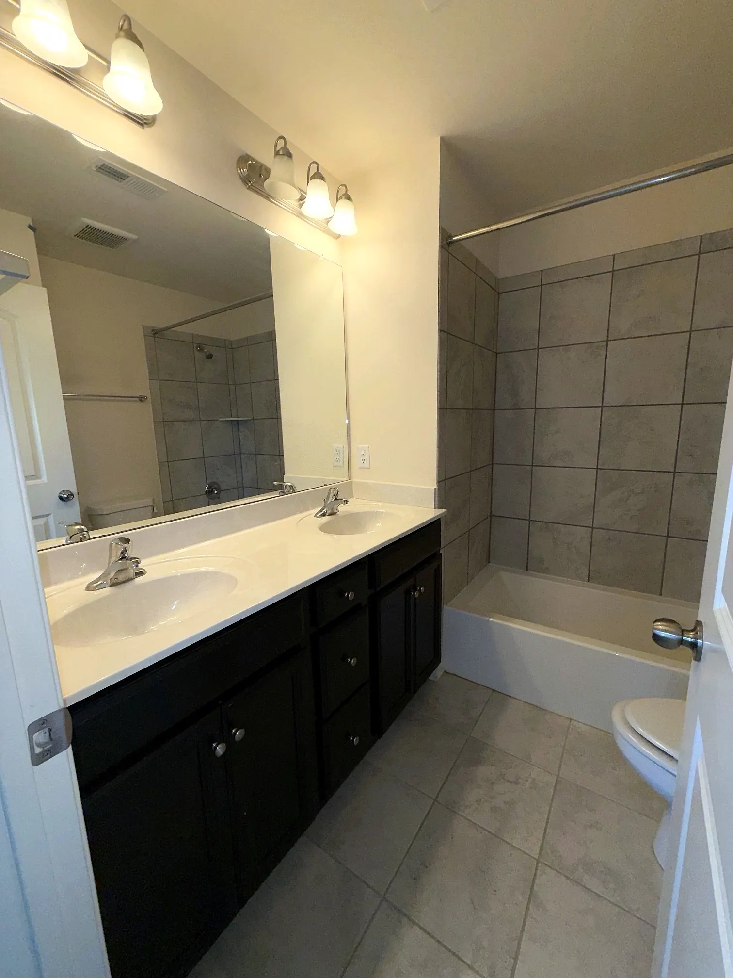 Full bath with double vanity and tiled tub and shower